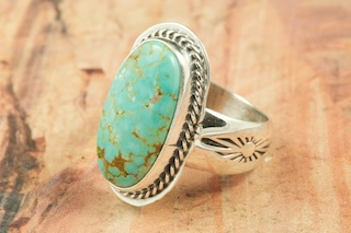 Genuine Number 8 Turquoise set in Sterling Silver Ring. The Number 8 mine is located in Eureka County Nevada. Since 1976 there has been no Number 8 Turquoise mined. There is however, an existing stock pile that Mr. Dowell Ward, the last owner of the Number 8 mine, had stocked away for later sorting. The Turquoise is a collector's item--because once the reserve is gone there will be no more material released onto the market. The Gold Mining Company owns the claim to the Number 8 mine and it has been swallowed up by the gold mining operations. This is some of the last Number 8 Turquoise to be had and will be a great addition to your collection. Created by Navajo Artist Lucy Valencia. Signed L. J. by the artist.
